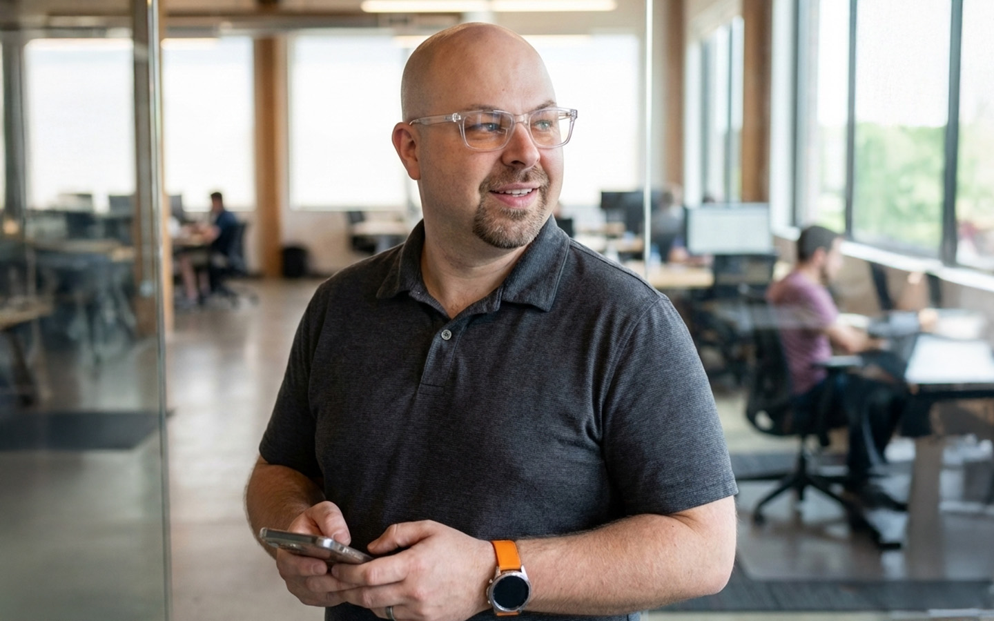 Simon in an open office looking down the hallway and holding a smart phone